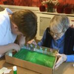 A woman and young lad working together to create a handmade football game