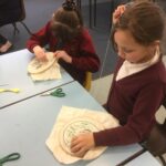 Two school girls embroidering pieces of fabric