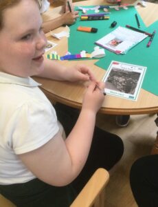 A school girl seated a table with a photograph of a football team in front of her