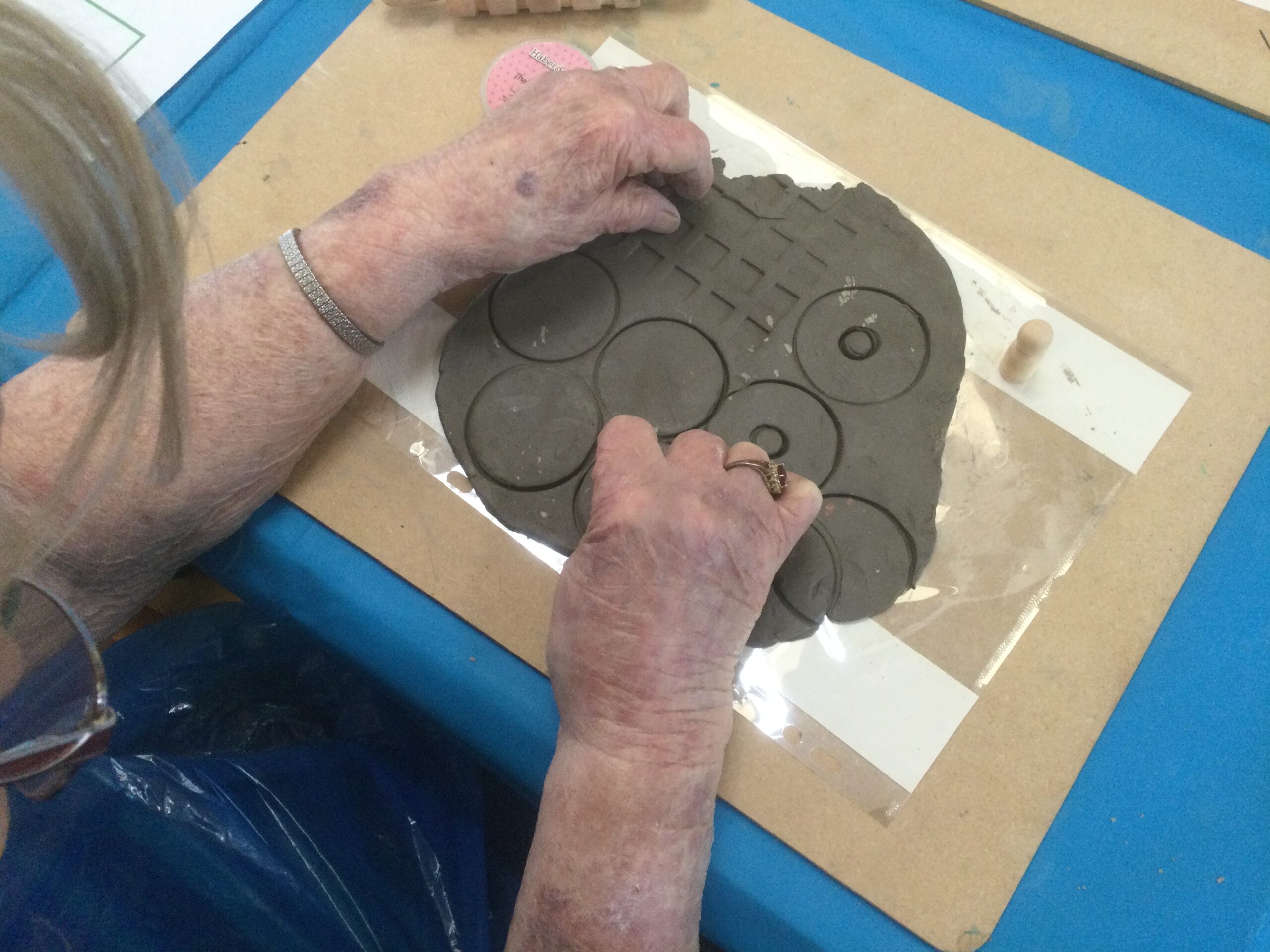 Overhead view of person making patterns in a slab of clay