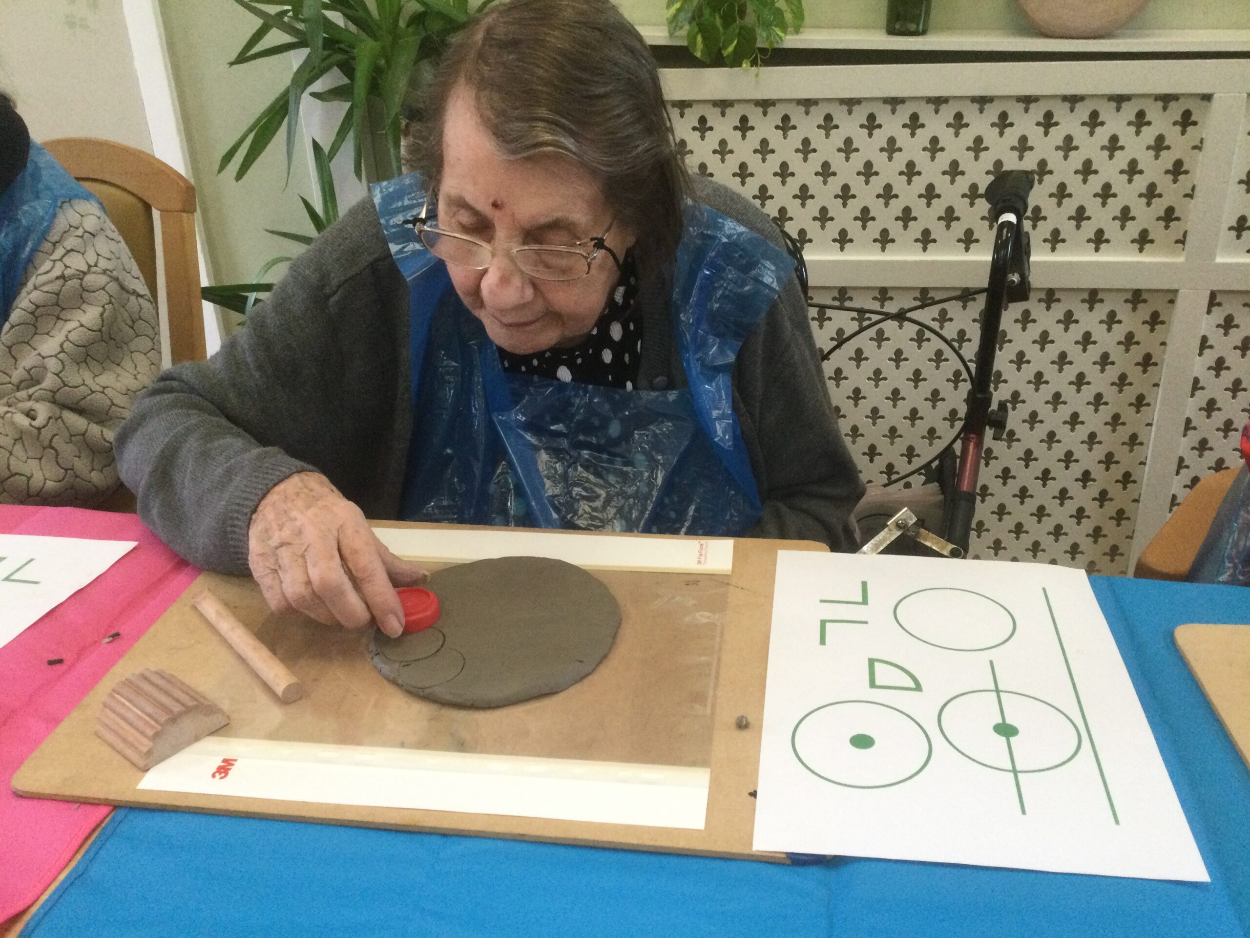 A woman carefully making impressions on a slab of clay