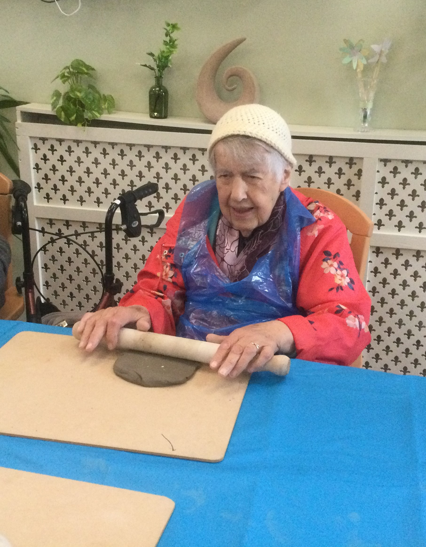 A woman smiles as she rolls out a piece of clay lump