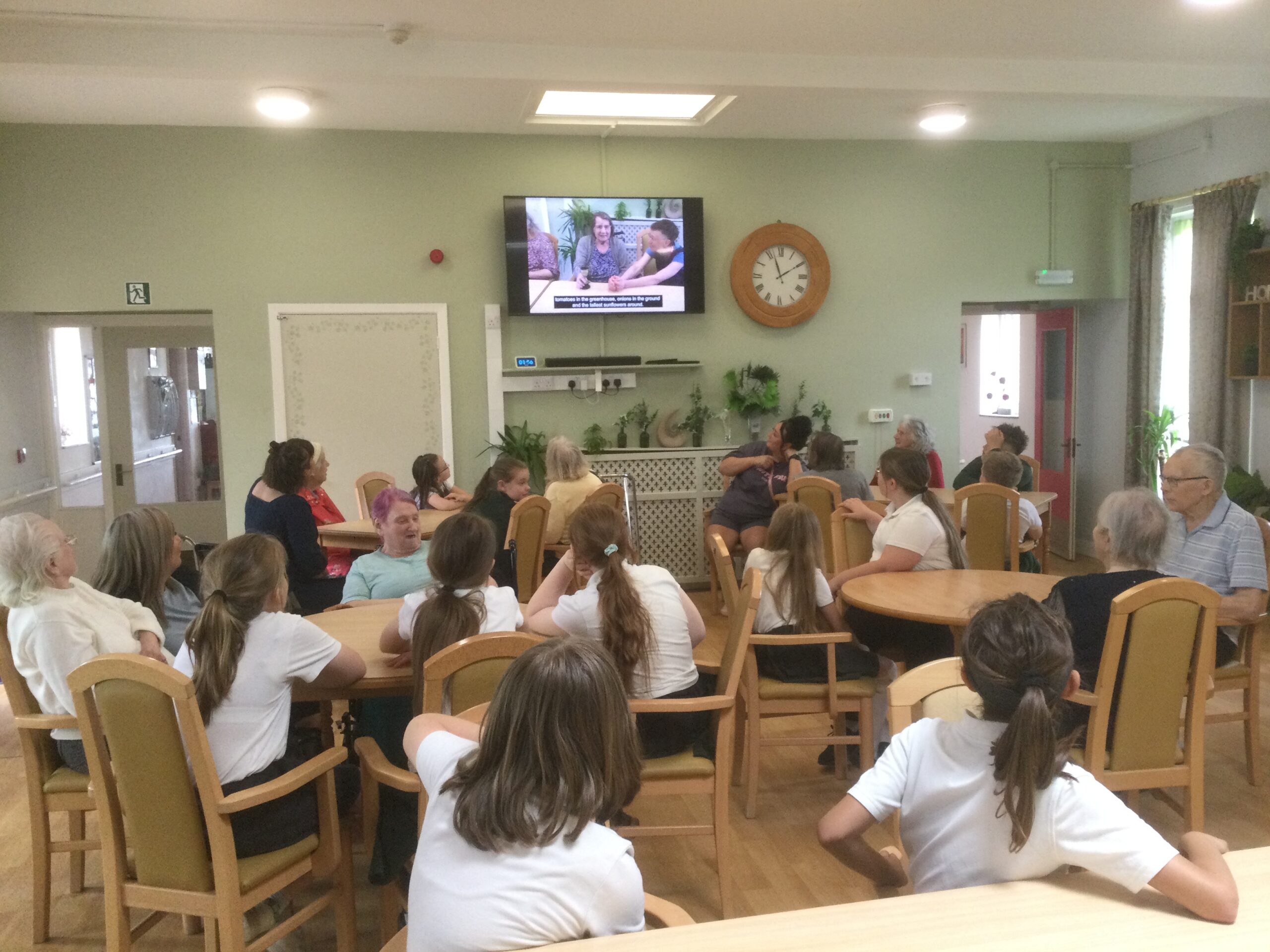 A room full of children and adults all watching a video screen