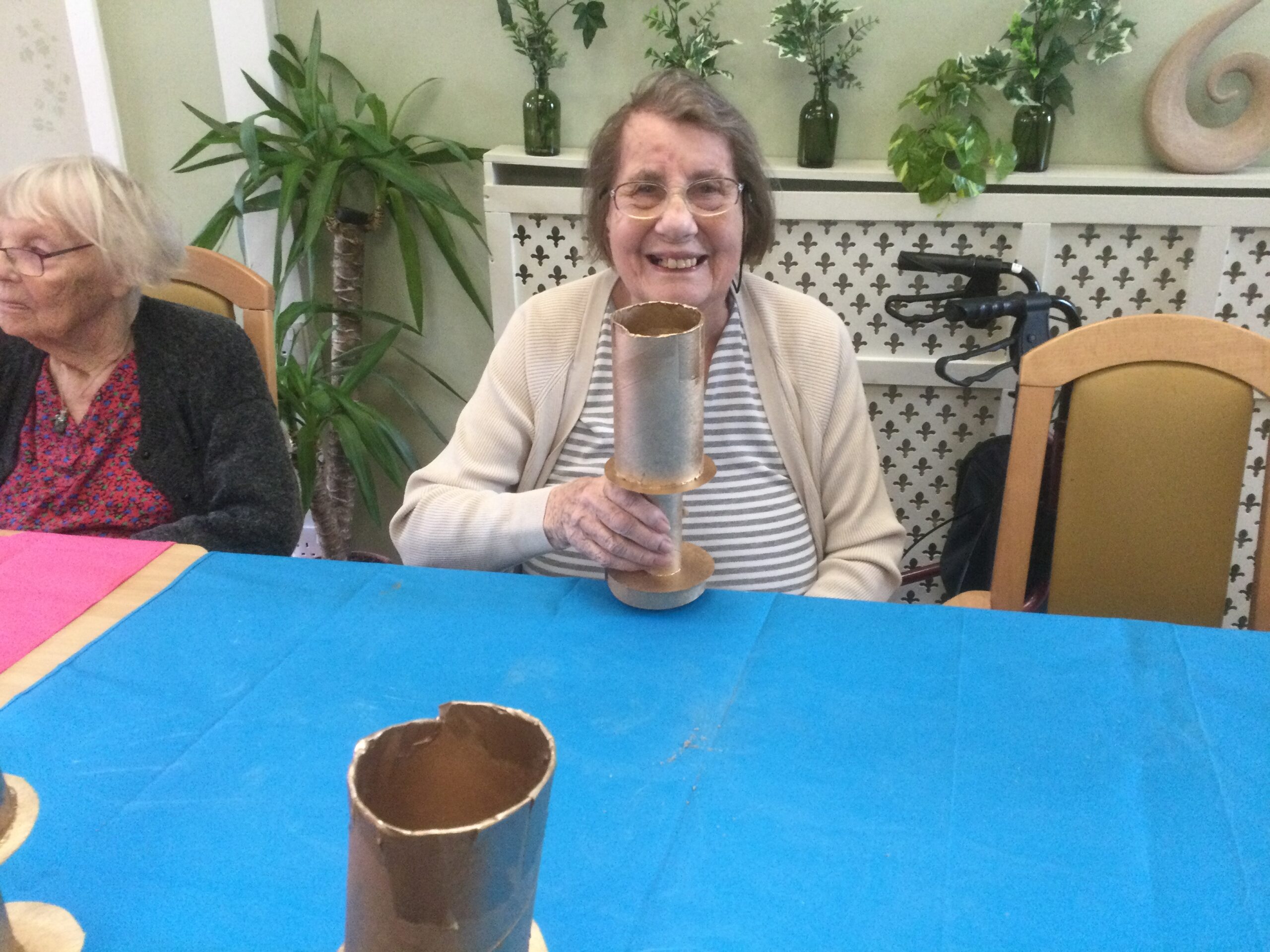 A woman smiles to camera, holding a gold-sprayed cardboard trophy