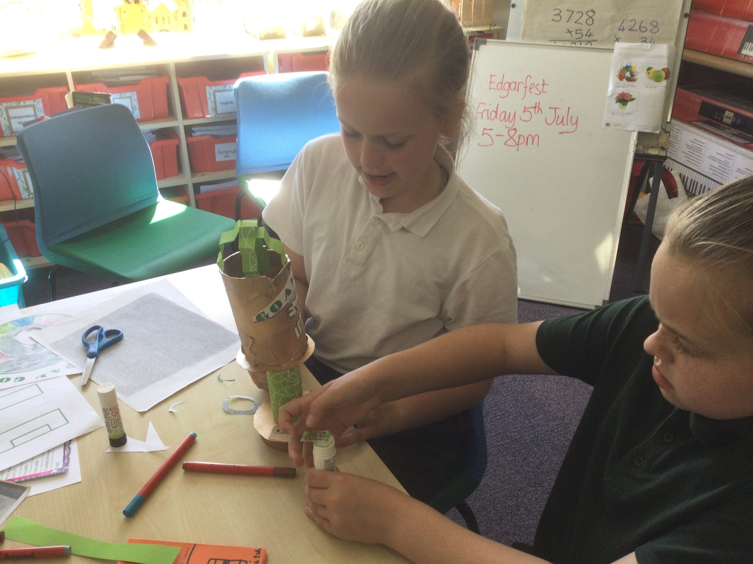 Two school girls applying fine details to their cardboard trophy