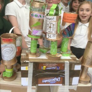 Close up of trophies on cardboard box stands with children behind