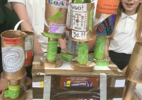 Close up of trophies on cardboard box stands with children behind