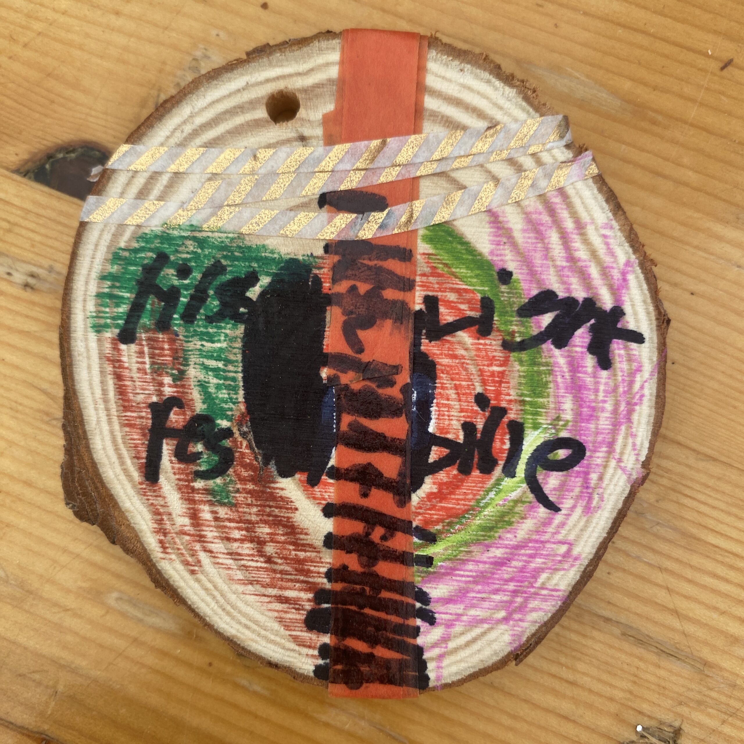 A colourful wooden disc with words First Light Festival