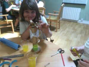 A child sits, face in hand, holding a piece of paper in place on her trophy, waiting for it to stick in place