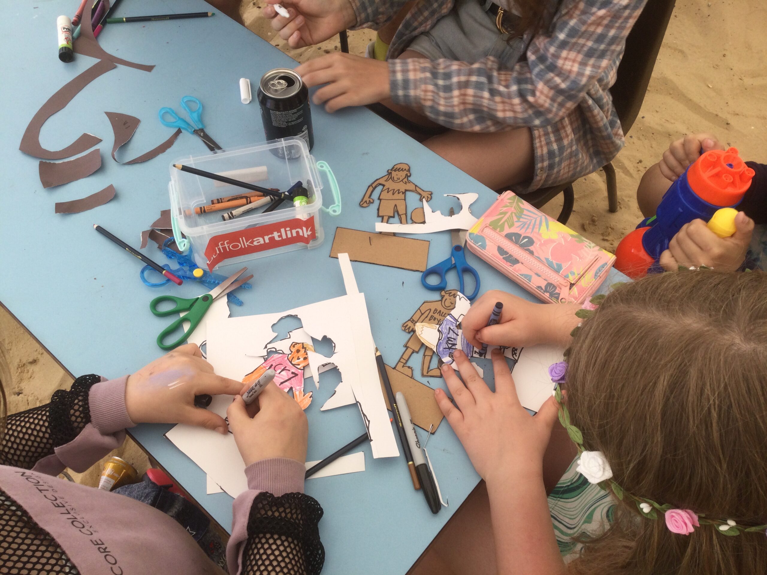 Overview of children cutting out and colouring in cardboard football figures