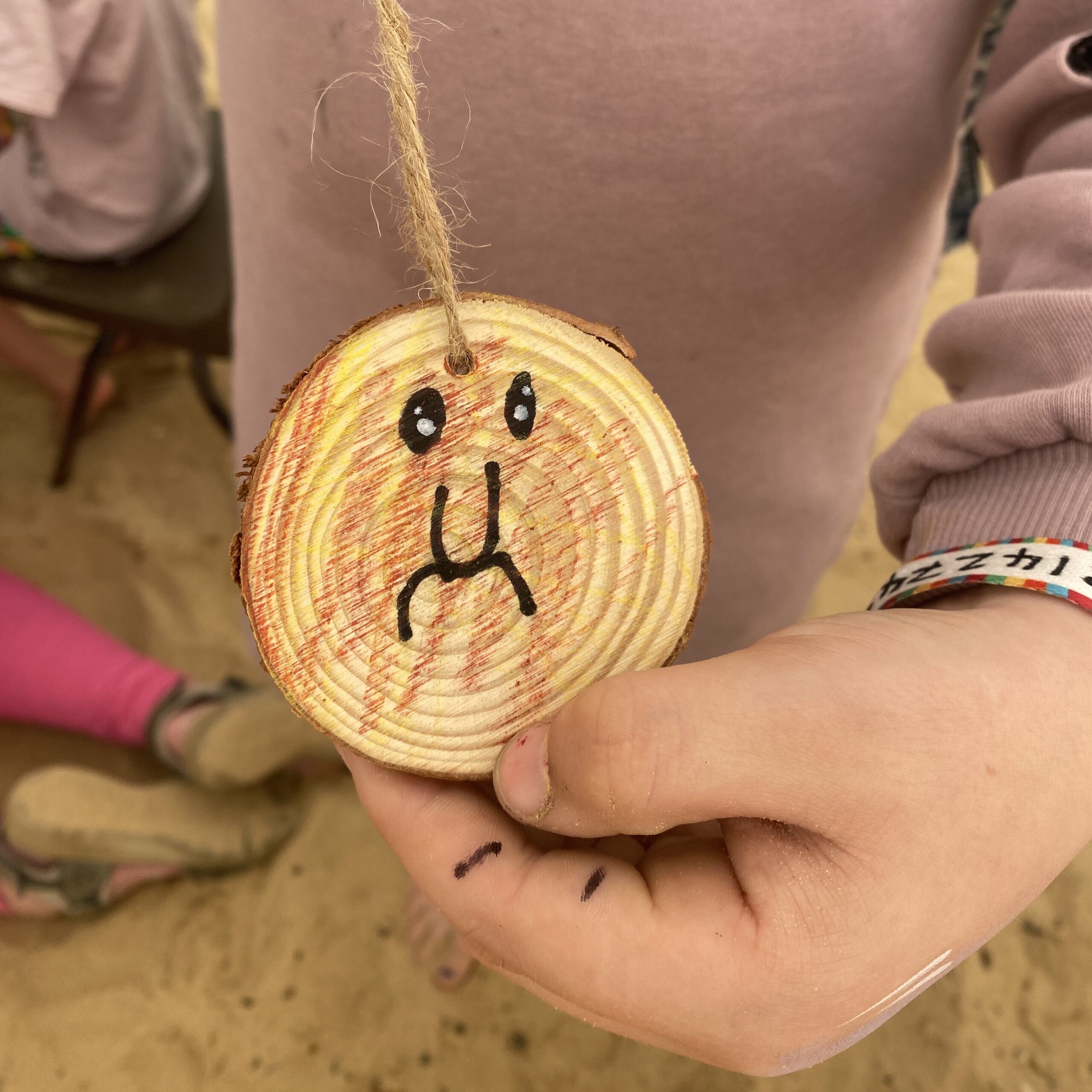 A child's hand holds up a colourful disc with a face on it