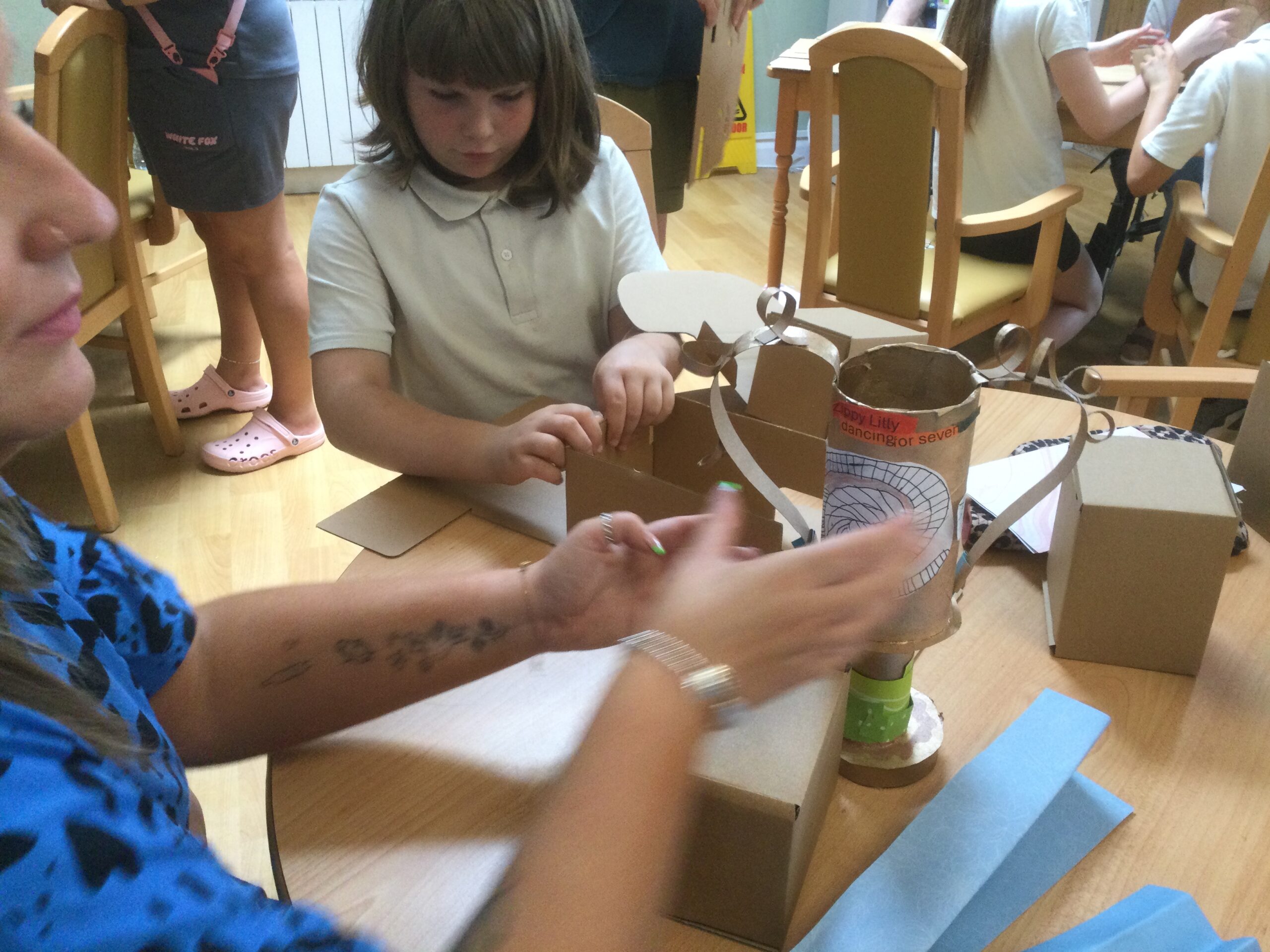 A table top covered in cardboard boxes and trophies, with a child making a cube