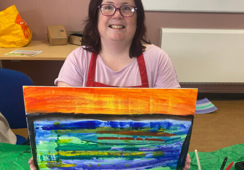 Laura holding her a dramatic landscape, horizontal bands of bright colours.