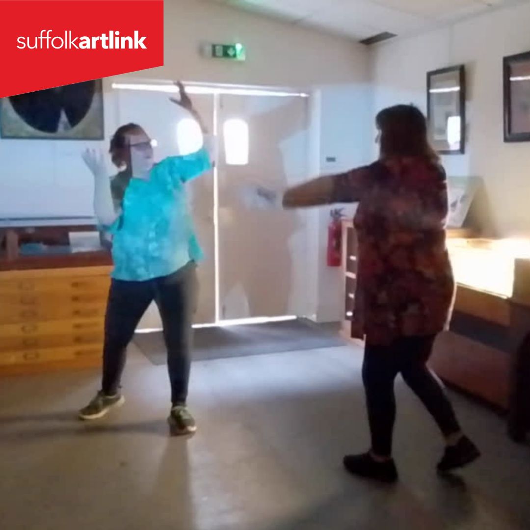 Two people doing a movement exercise in the light from a projector.