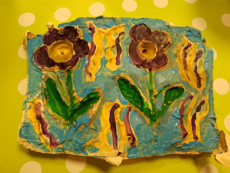 A plaster cast of colourful flowers against a sunny, yellow background