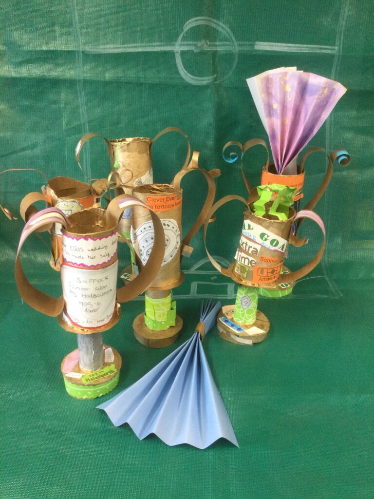 Six decorated gold trophies on a green background