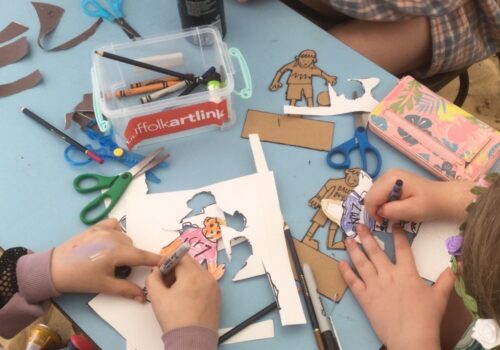 Overview of children cutting out and colouring in cardboard football figures