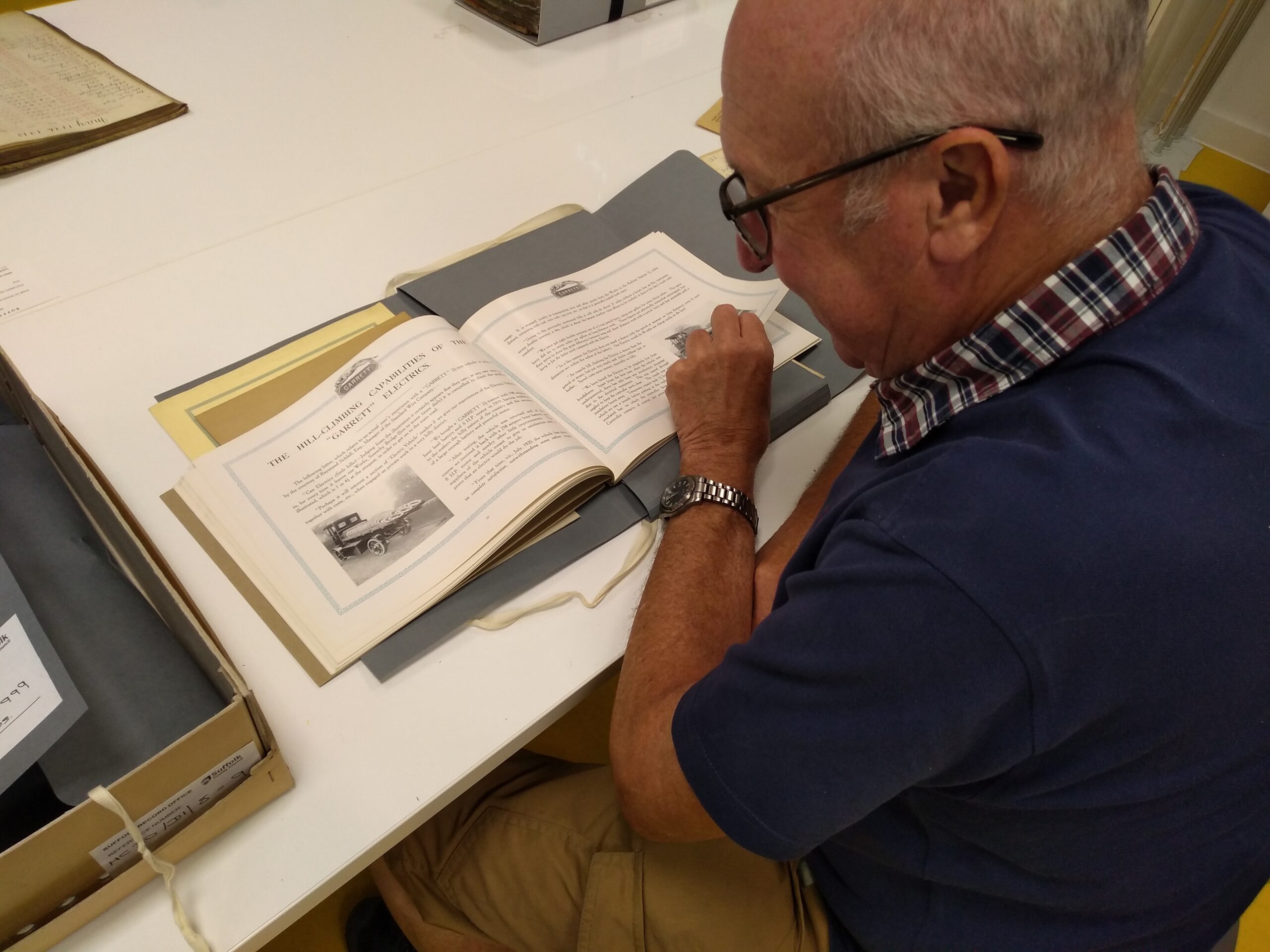 An adult looking at an old book about Garretts with this page showing an image and text relating to the Hill Climbing Capabilities of the Garrett Electrics