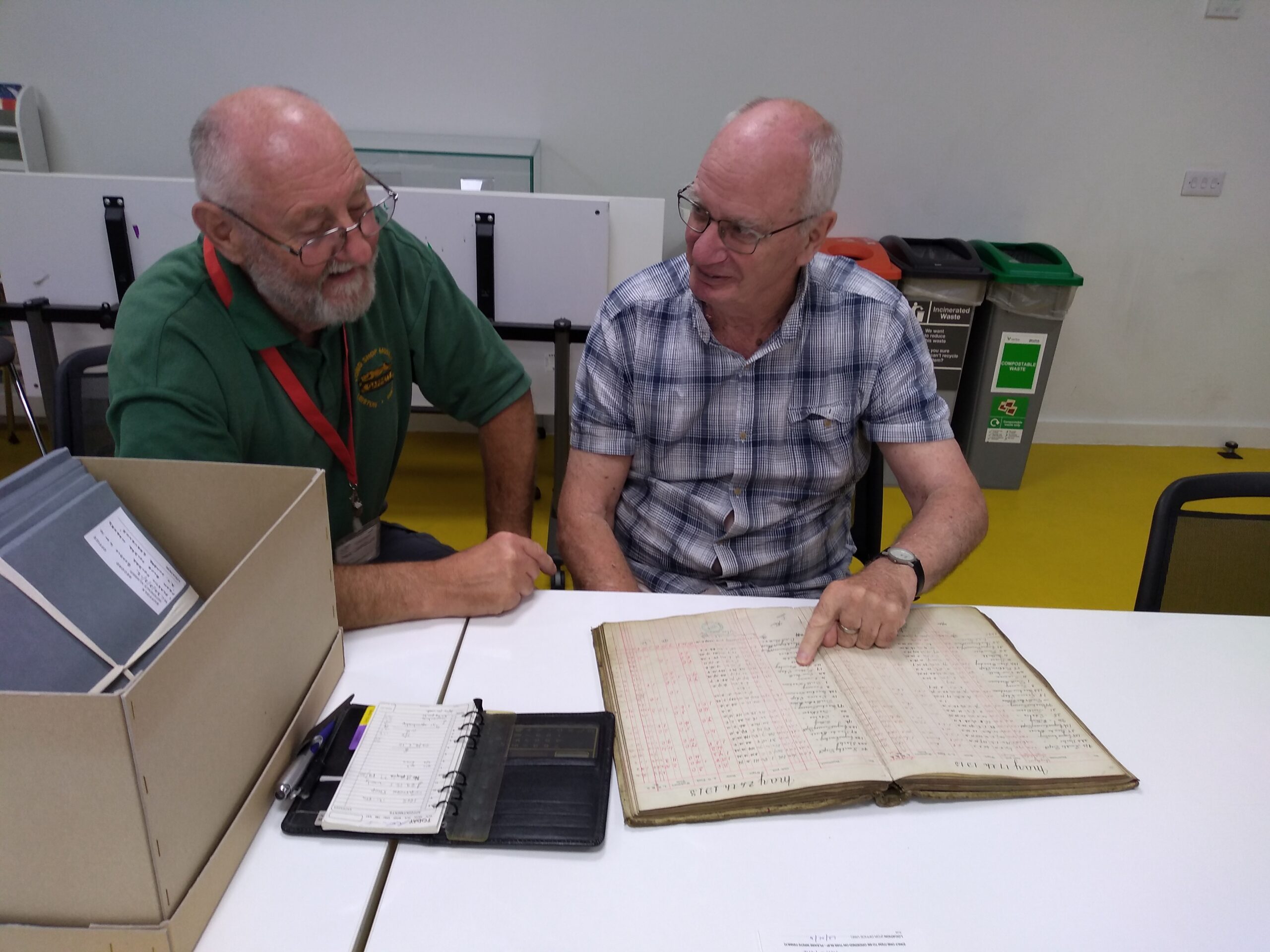 A adult males examining an old wages book from Garretts Engineering Works, dating back to 1913