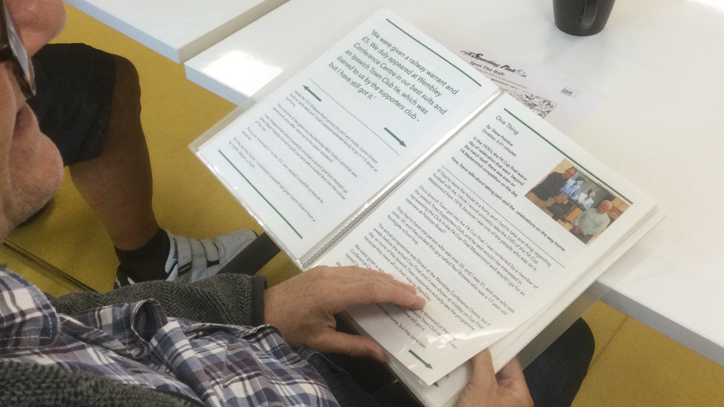 Overhead view of person reading on of the Extra Time footballing stories. The person's hand rests on the bottom of the page.