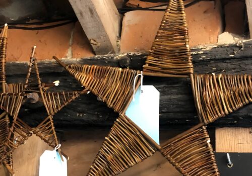 A large and a small willow star hanging on a barn wall.