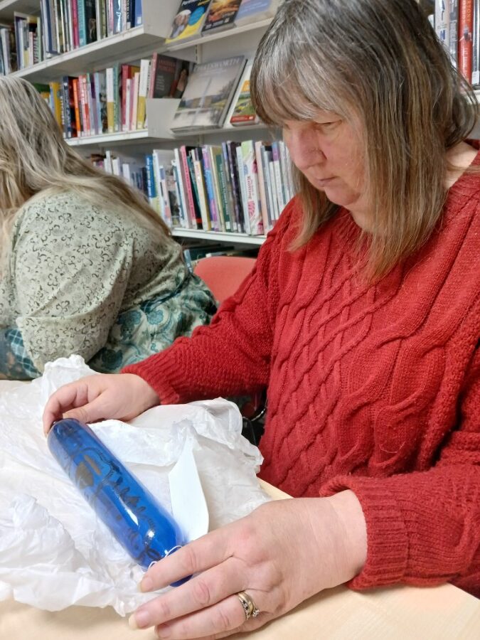 Woman examines blue glass rolling pin - artefact from the Food Museum.