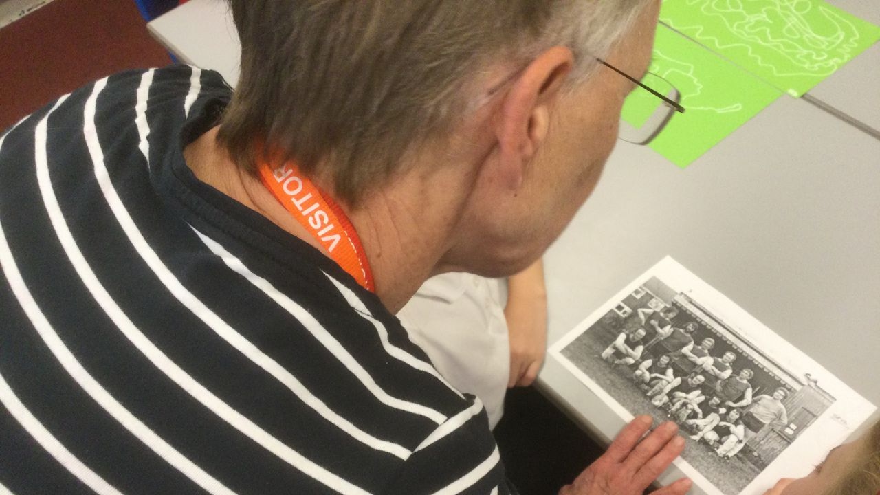 An overhead view of an adult studying a monochrome photograph of a football team