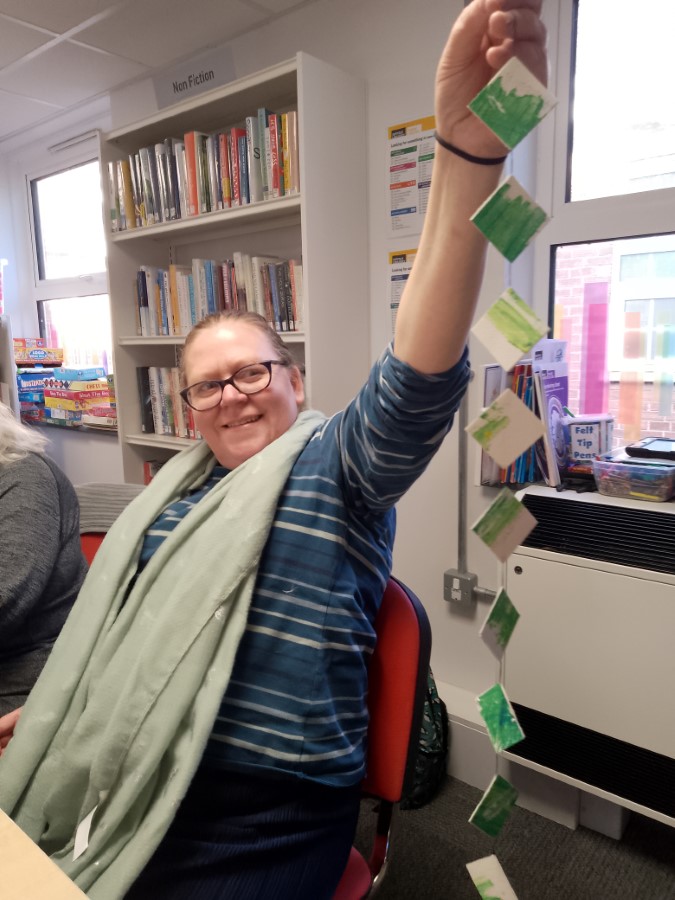 woman holds a strong of decorated paper cubes