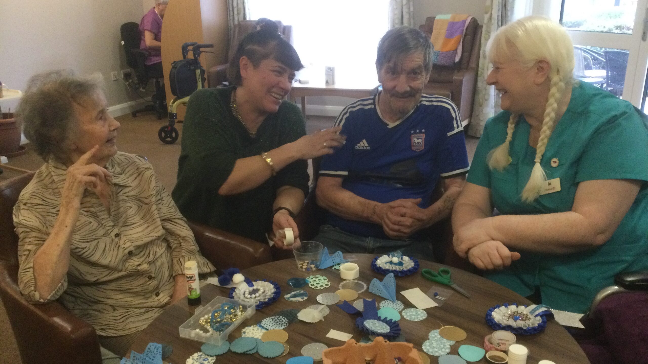 Four adults seated around a table covered in craft materials