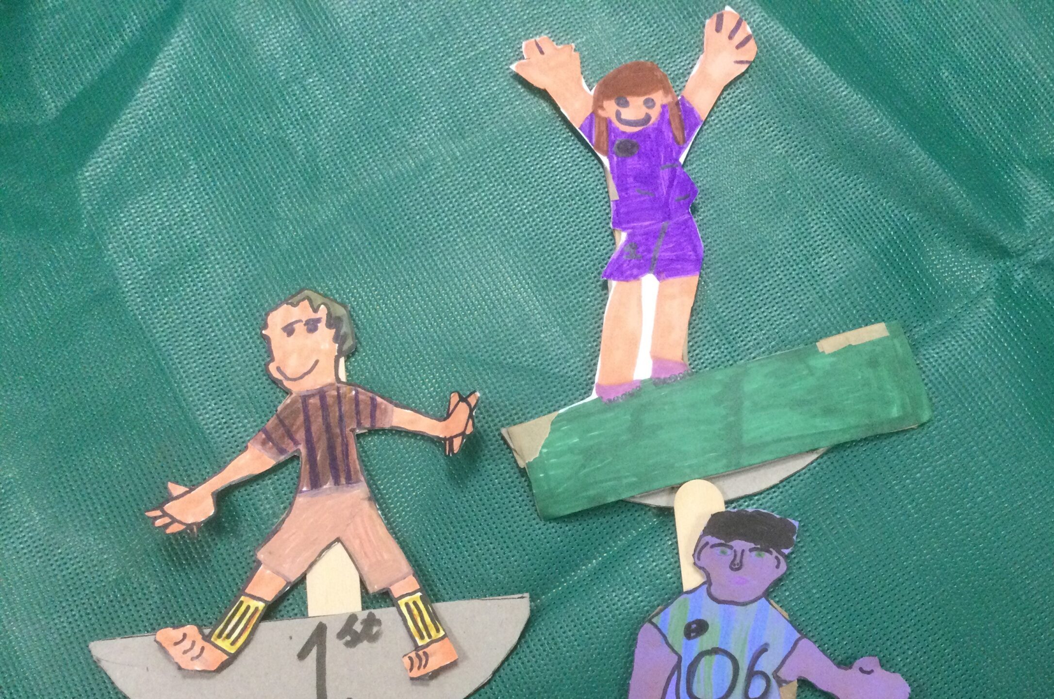 3 football figures, one with hands up in the air on green background