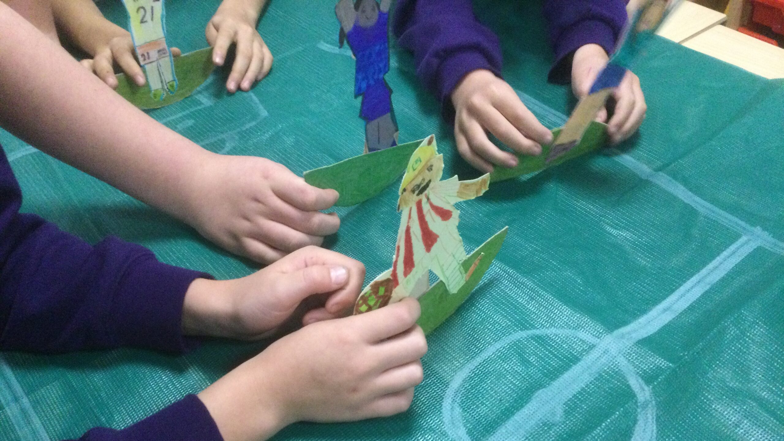 Children playing table top football with their cardboard figures