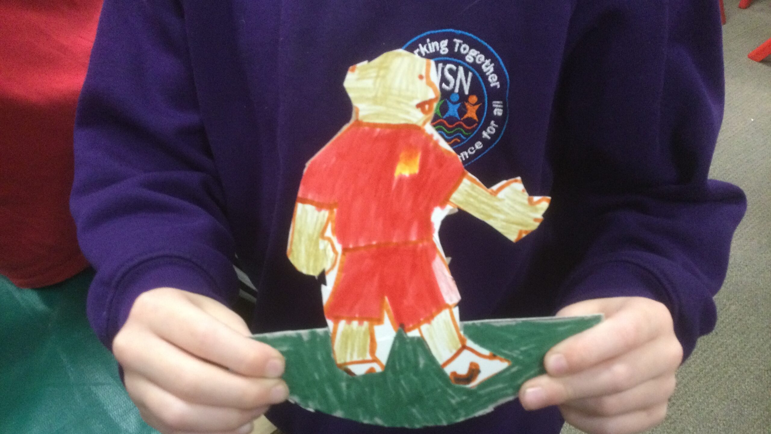 A child holds the football figure he made, dressed in bright red kit