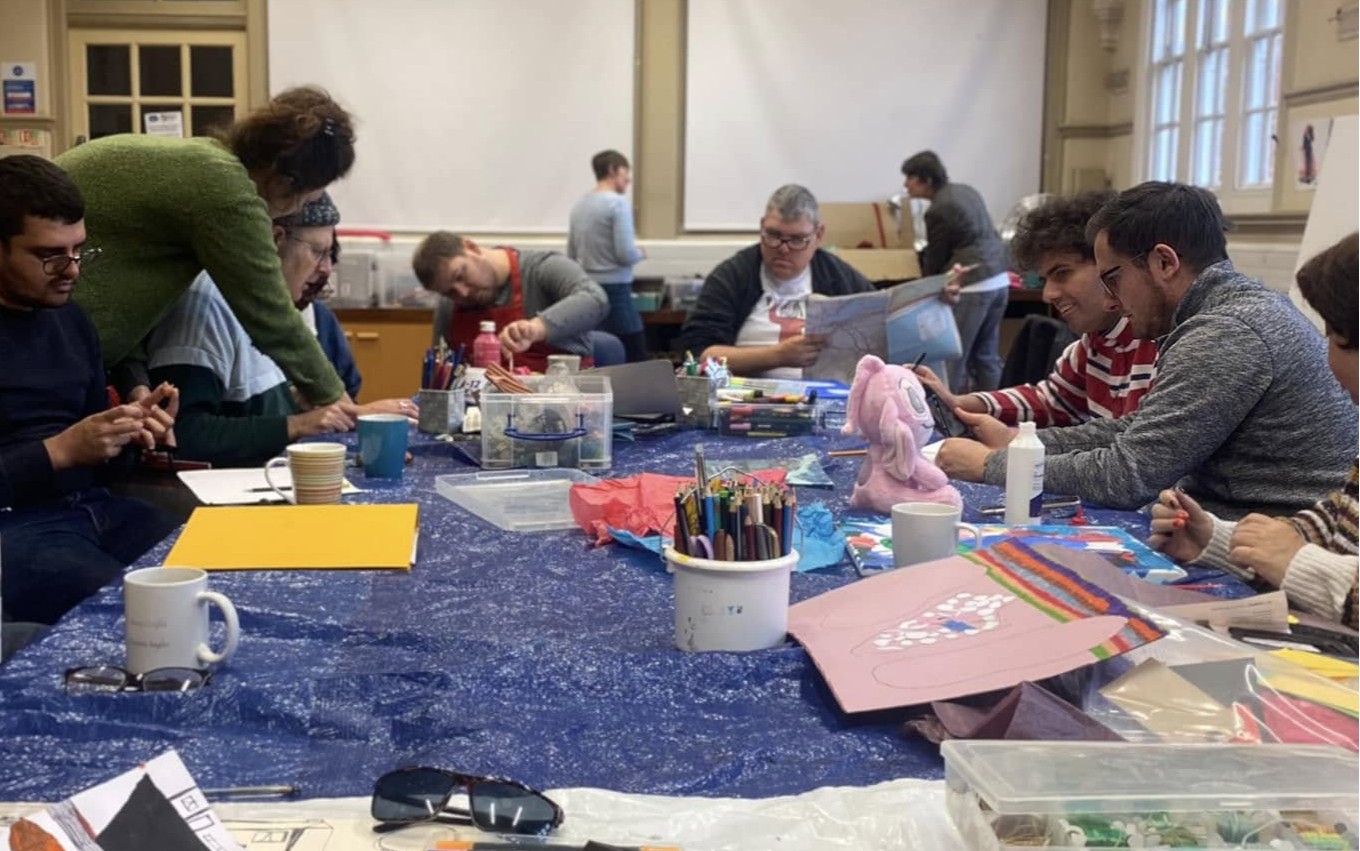 Brave artists making their artwork around a large central table.