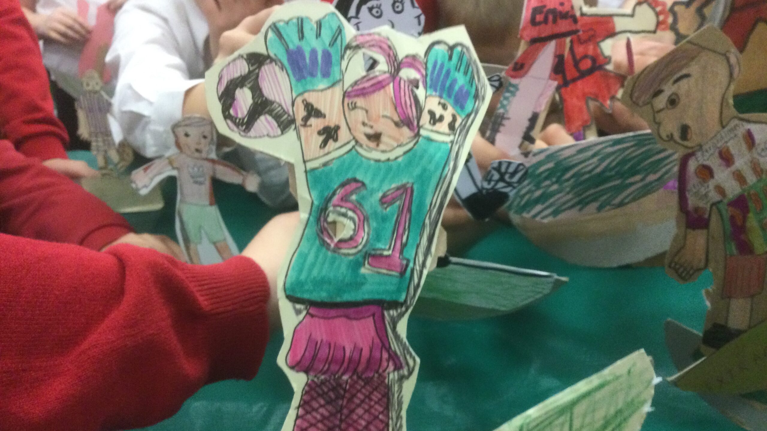 A cardboard figure of a football player wearing a jersey with 61 on it and her arms up in the air she is surrounded by other players