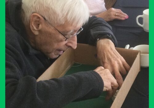 A gentleman concentrates on drawing round an object inside a cardboard box