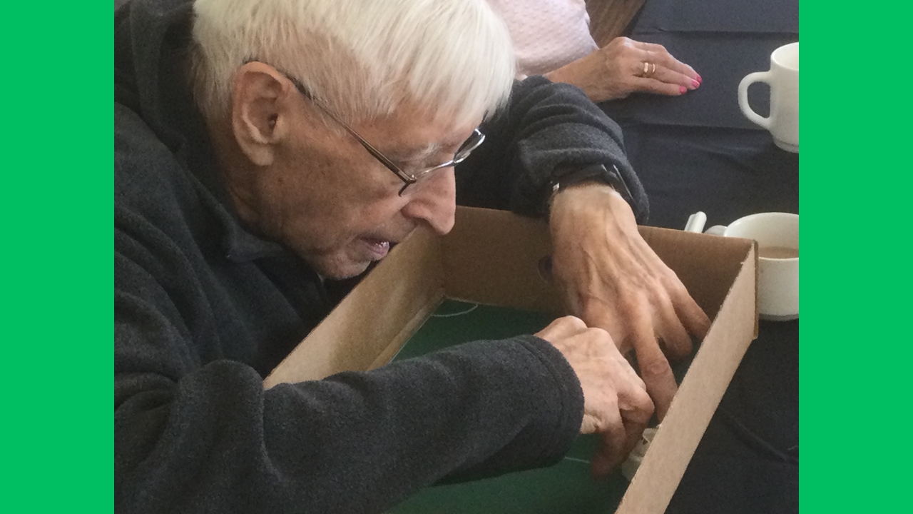 A gentleman concentrates on drawing round an object inside a cardboard box