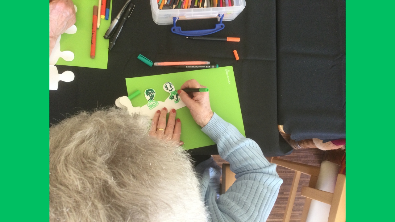 Overhead view of a woman drawing faces on a row of paper people