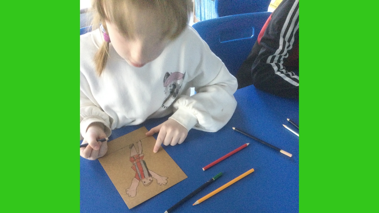 Overhead image of child drawing a football figure on a brown background