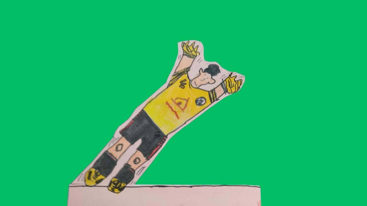 A cut-out football figure in a yellow and black jersey and black shorts wearing yellow goalie gloves