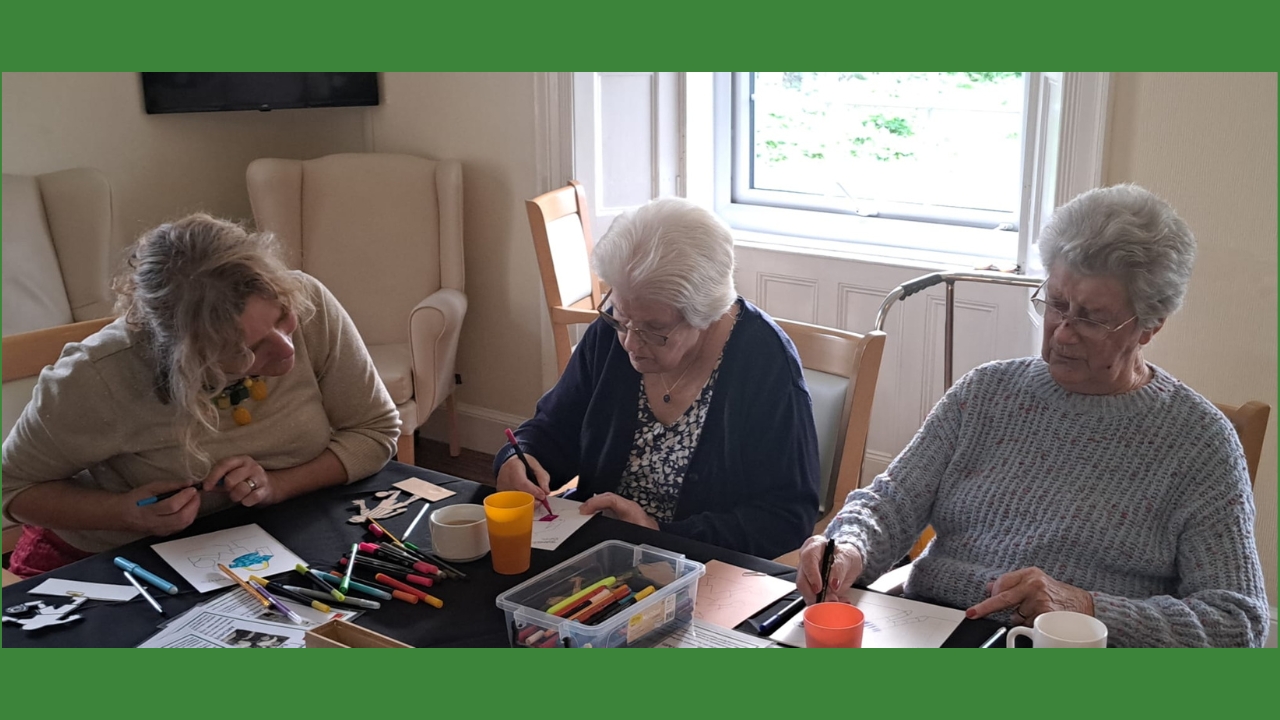 Two residents seated side by side with Kate looking on as they create their individual football characters