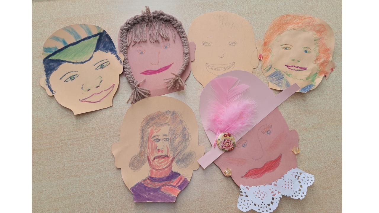 Six paper faces each decorated differently, some with woollen plaits and one in a blue and green peaked cap