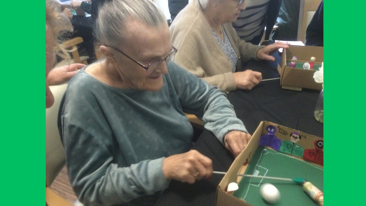 Two ladies seated side by side, each playing a game of magnetic football